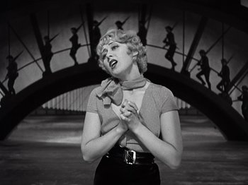 Movie still from “Gold Diggers of 1933” (1933), directed by Mervyn LeRoy – An old photo of a woman holding her hands in prayer; Medium shot, Low angle