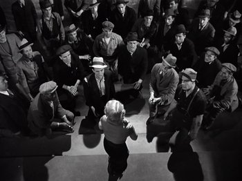 Movie still from “Gold Diggers of 1933” (1933), directed by Mervyn LeRoy – A group of men sitting in a room with a woman; Wide shot, High angle