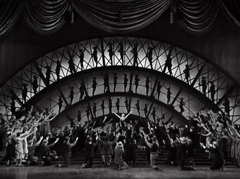 Movie still from “Gold Diggers of 1933” (1933), directed by Mervyn LeRoy – A black and white photo of a group of people performing a dance; Extreme Wide shot, Low angle