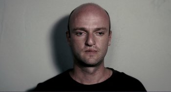 Movie still from “Gone Baby Gone” (2007), directed by Ben Affleck – A man with a shaved head is looking at the camera; Close Up shot, Low angle