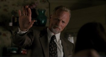 Movie still from “Gone Baby Gone” (2007), directed by Ben Affleck – An older man wearing a suit and tie holding a cigarette; Close Up shot, Low angle