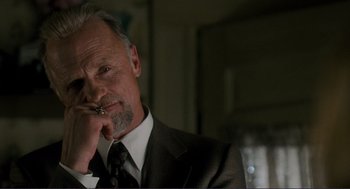 Movie still from “Gone Baby Gone” (2007), directed by Ben Affleck – An older man wearing a suit and tie holding a cigarette; Close Up shot, Low angle