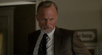 Movie still from “Gone Baby Gone” (2007), directed by Ben Affleck – An older man in a suit and tie looking at the camera; Close Up shot, Low angle
