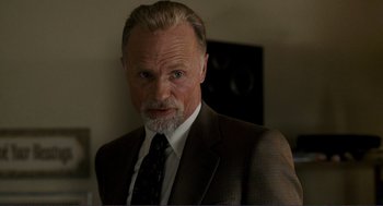 Movie still from “Gone Baby Gone” (2007), directed by Ben Affleck – An older man in a brown suit and a white beard; Close Up shot, Over the shoulder angle