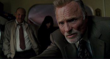 Movie still from “Gone Baby Gone” (2007), directed by Ben Affleck – An older man in a suit and tie looking at the camera; Close Up shot, Low angle