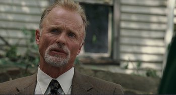 Movie still from “Gone Baby Gone” (2007), directed by Ben Affleck – An older man in a suit and tie looking to his left; Close Up shot, Low angle