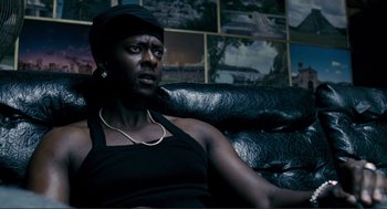 Movie still from “Gone Baby Gone” (2007), directed by Ben Affleck – A woman sitting on a couch in front of a wall of pictures; Close Up shot, Over the shoulder angle