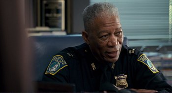 Movie still from “Gone Baby Gone” (2007), directed by Ben Affleck – An older police officer sitting at a desk looking at his cell phone; Close Up shot, Over the shoulder angle