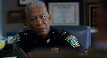 Movie still from “Gone Baby Gone” (2007), directed by Ben Affleck – An older police officer sitting at a table; Close Up shot, Over the shoulder angle