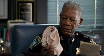 Movie still from “Gone Baby Gone” (2007), directed by Ben Affleck – A police officer is holding a cloth in his hand; Close Up shot, Over the shoulder angle