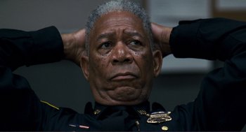 Movie still from “Gone Baby Gone” (2007), directed by Ben Affleck – An older man in a police uniform is holding his hands behind his head; Close Up shot, Low angle