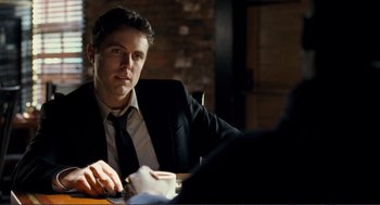 Movie still from “Gone Baby Gone” (2007), directed by Ben Affleck – A man sitting at a table in front of a brick wall; Close Up shot, Over the shoulder angle