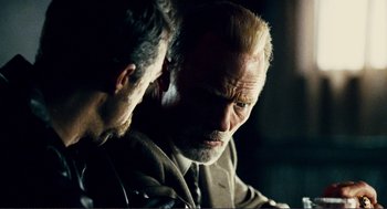 Movie still from “Gone Baby Gone” (2007), directed by Ben Affleck – A man sitting next to another man in a dark room; Close Up shot, Over the shoulder angle