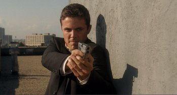 Movie still from “Gone Baby Gone” (2007), directed by Ben Affleck – A man in a suit and tie holding a gun in his hand; Close Up shot, Low angle