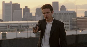 Movie still from “Gone Baby Gone” (2007), directed by Ben Affleck – A man in a suit and tie holding a gun; Medium shot, Low angle