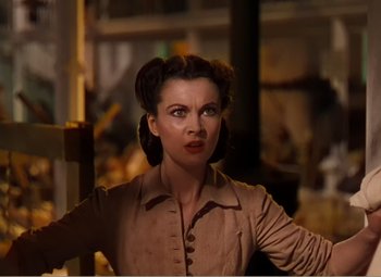 Movie still from “Gone with the Wind” (1939), directed by George Cukor – A woman in a brown shirt is standing in front of a building; Close Up shot, Low angle