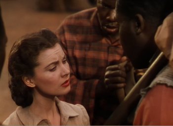 Movie still from “Gone with the Wind” (1939), directed by George Cukor – A woman in a plaid shirt is talking to two men; Close Up shot, High angle