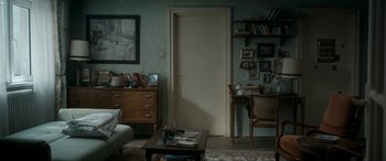 Movie still from “Graduation” (2016), directed by Cristian Mungiu – A living room with a table , chair , and a door; Wide shot, High angle