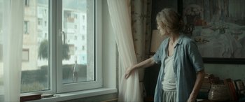 Movie still from “Graduation” (2016), directed by Cristian Mungiu – A woman standing in front of a window looking outside; Medium shot, Over the shoulder angle