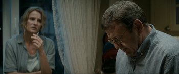 Movie still from “Graduation” (2016), directed by Cristian Mungiu – An older man wearing glasses looking down at a curtain; Close Up shot, Over the shoulder angle