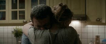Movie still from “Graduation” (2016), directed by Cristian Mungiu – A man and a woman hugging each other in a darkened room; Close Up shot, Over the shoulder angle