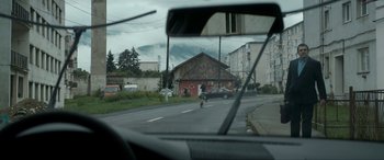 Movie still from “Graduation” (2016), directed by Cristian Mungiu – A person riding a bike down a street; Extreme Wide shot, Over the shoulder angle