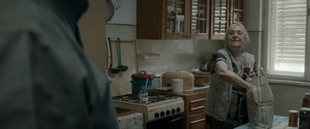 Movie still from “Graduation” (2016), directed by Cristian Mungiu – A woman standing next to a stove in a kitchen; Medium shot, Over the shoulder angle
