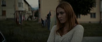 Movie still from “Graduation” (2016), directed by Cristian Mungiu – A red haired woman in a white sweater looking to her left; Close Up shot, Low angle