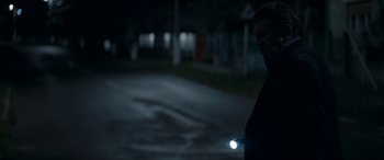 Movie still from “Graduation” (2016), directed by Cristian Mungiu – A man is holding a flashlight on the side of the road; Medium shot, Over the shoulder angle