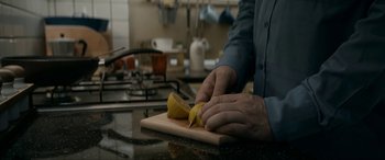 Movie still from “Graduation” (2016), directed by Cristian Mungiu – A person cutting a banana on a cutting board; Extreme Close Up shot, High angle