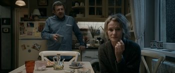 Movie still from “Graduation” (2016), directed by Cristian Mungiu – A man and a woman sitting at a table in a kitchen; Medium shot, Over the shoulder angle