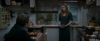 Movie still from “Graduation” (2016), directed by Cristian Mungiu – A woman standing in front of a counter holding a plate; Medium shot, Over the shoulder angle