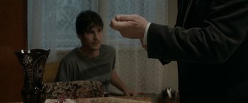 Movie still from “Graduation” (2016), directed by Cristian Mungiu – A man in a suit is giving a piece of pizza to another man; Close Up shot, Over the shoulder angle