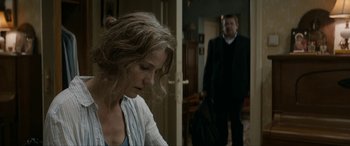 Movie still from “Graduation” (2016), directed by Cristian Mungiu – A man and a woman standing in front of a door; Medium shot, Over the shoulder angle