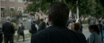 Movie still from “Graduation” (2016), directed by Cristian Mungiu – A person wearing a suit and glasses; Close Up shot, Over the shoulder angle