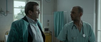 Movie still from “Graduation” (2016), directed by Cristian Mungiu – Two men standing in front of each other in a room; Medium shot, Over the shoulder angle