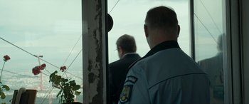 Movie still from “Graduation” (2016), directed by Cristian Mungiu – Two men in suits are standing next to each other; Close Up shot, Over the shoulder angle