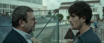 Movie still from “Graduation” (2016), directed by Cristian Mungiu – Two men are standing in front of a fence; Close Up shot, Over the shoulder angle
