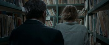 Movie still from “Graduation” (2016), directed by Cristian Mungiu – A man and a woman in front of a book shelf; Medium shot, Over the shoulder angle