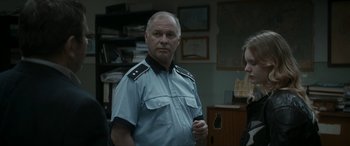 Movie still from “Graduation” (2016), directed by Cristian Mungiu – A man in a police uniform standing next to a woman; Medium shot, Over the shoulder angle
