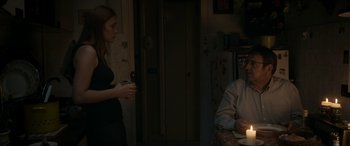 Movie still from “Graduation” (2016), directed by Cristian Mungiu – Two people are standing in a dimly - lit room; Medium shot, Over the shoulder angle