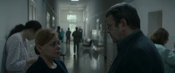 Movie still from “Graduation” (2016), directed by Cristian Mungiu – A man and a woman are talking in a hallway; Medium shot, Over the shoulder angle