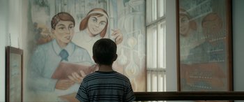 Movie still from “Graduation” (2016), directed by Cristian Mungiu – A young boy standing in front of a painting; Medium shot, Over the shoulder angle