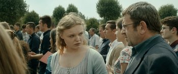 Movie still from “Graduation” (2016), directed by Cristian Mungiu – A group of people standing in a line with trees in the background; Close Up shot, Over the shoulder angle