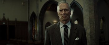 Movie still from “Gran Torino” (2008), directed by Clint Eastwood – An older man wearing a suit and tie in front of a church; Close Up shot, Low angle