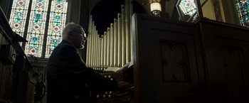 Movie still from “Gran Torino” (2008), directed by Clint Eastwood – An older man playing a pipe organ in a church; Medium shot, Low angle