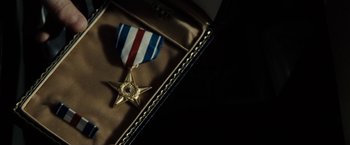 Movie still from “Gran Torino” (2008), directed by Clint Eastwood – A gold medal sitting on top of an award case; Extreme Close Up shot, Overhead angle