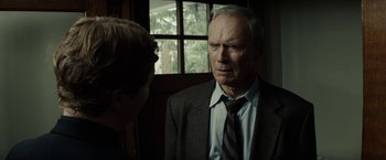 Movie still from “Gran Torino” (2008), directed by Clint Eastwood – An older man wearing a suit and tie talking to a young boy; Close Up shot, Over the shoulder angle