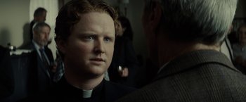 Movie still from “Gran Torino” (2008), directed by Clint Eastwood – A man in a clergyman's outfit talking to another man in a suit; Close Up shot, Over the shoulder angle