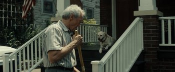 Movie still from “Gran Torino” (2008), directed by Clint Eastwood – An older man holding a baseball bat near a dog; Medium shot, Over the shoulder angle